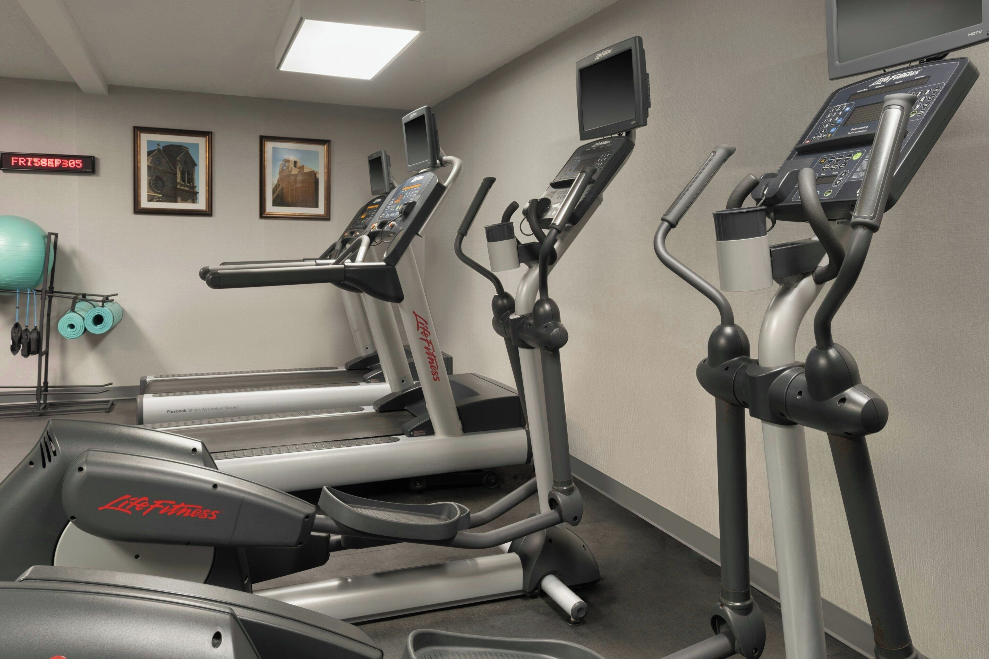 Un gimnasio con cintas de correr, una bicicleta estática y una máquina de remo.