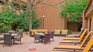 An outdoor patio with seating arrangements, including tables and chairs, and a lounge area with sun loungers.