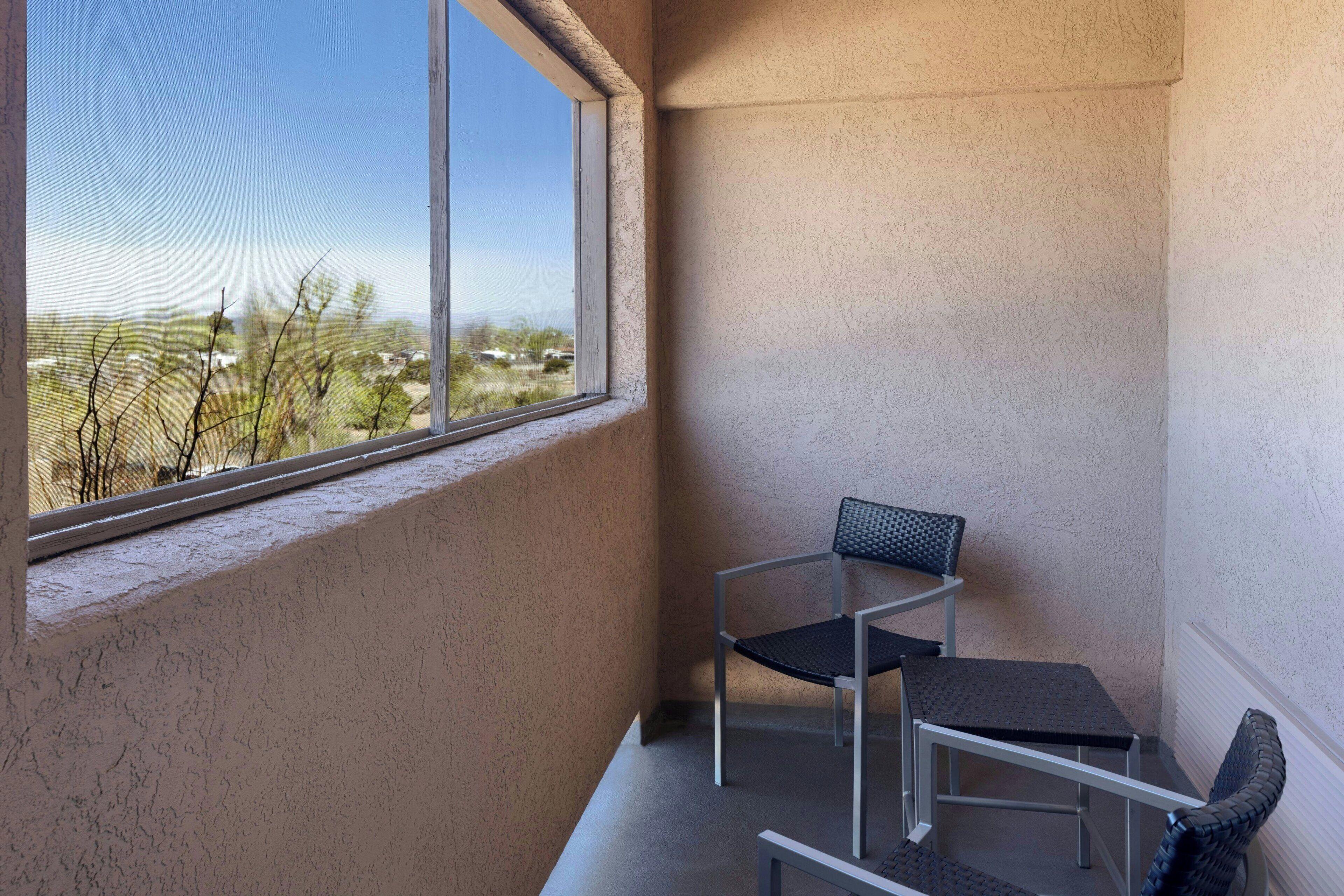 A balcony with a view of a landscape, a chair, and a table.