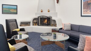 A modern living room with a fireplace, comfortable seating, and a large window.