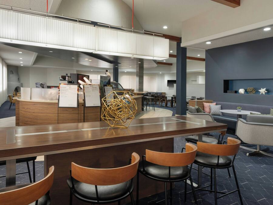 Een moderne bar met houten barkrukken en een decoratief kunstwerk met geometrische vormen.