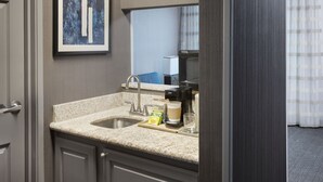 A hotel bathroom with a sink, mirror, and coffee maker.