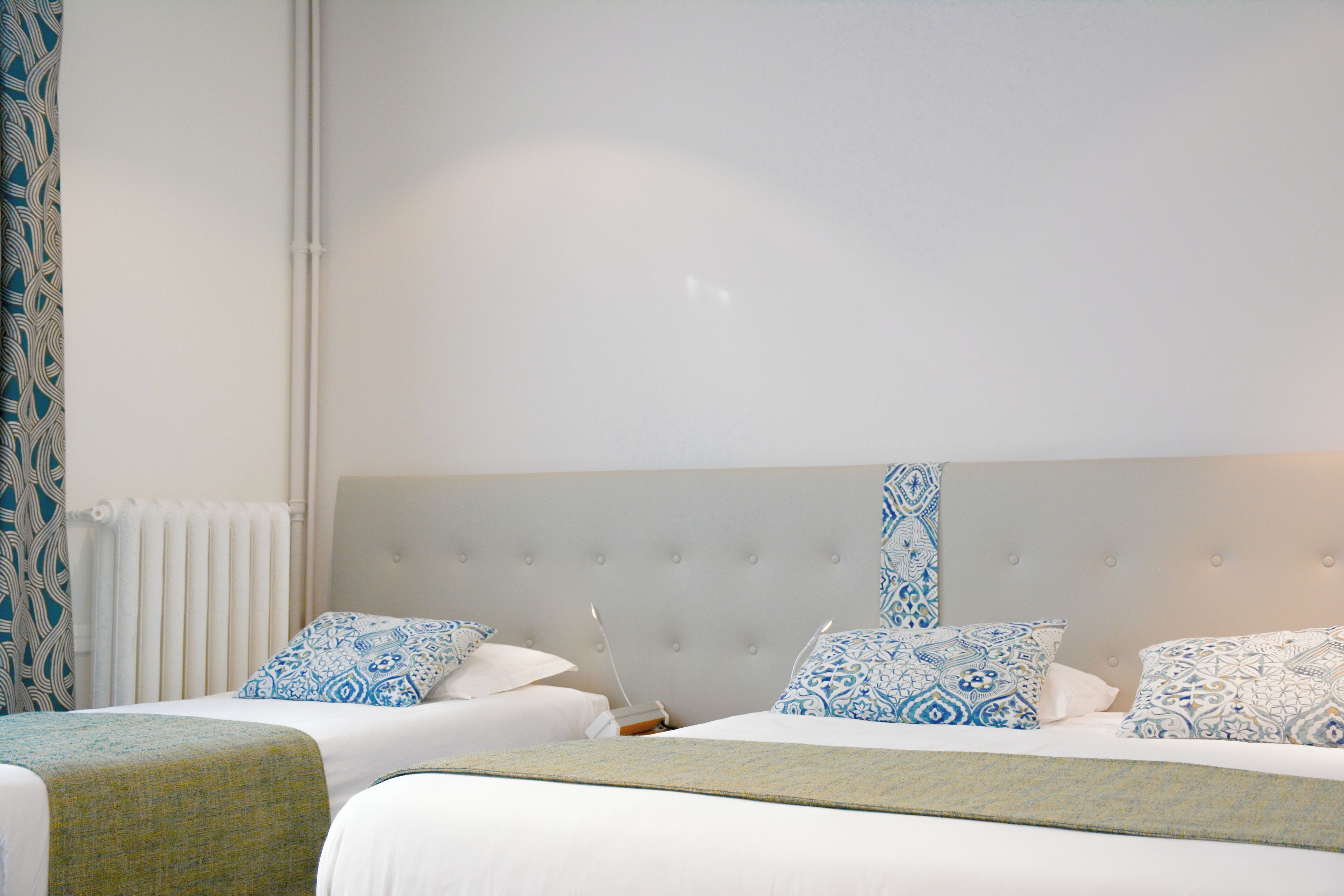 A hotel room with two beds, a large window, and a radiator.
