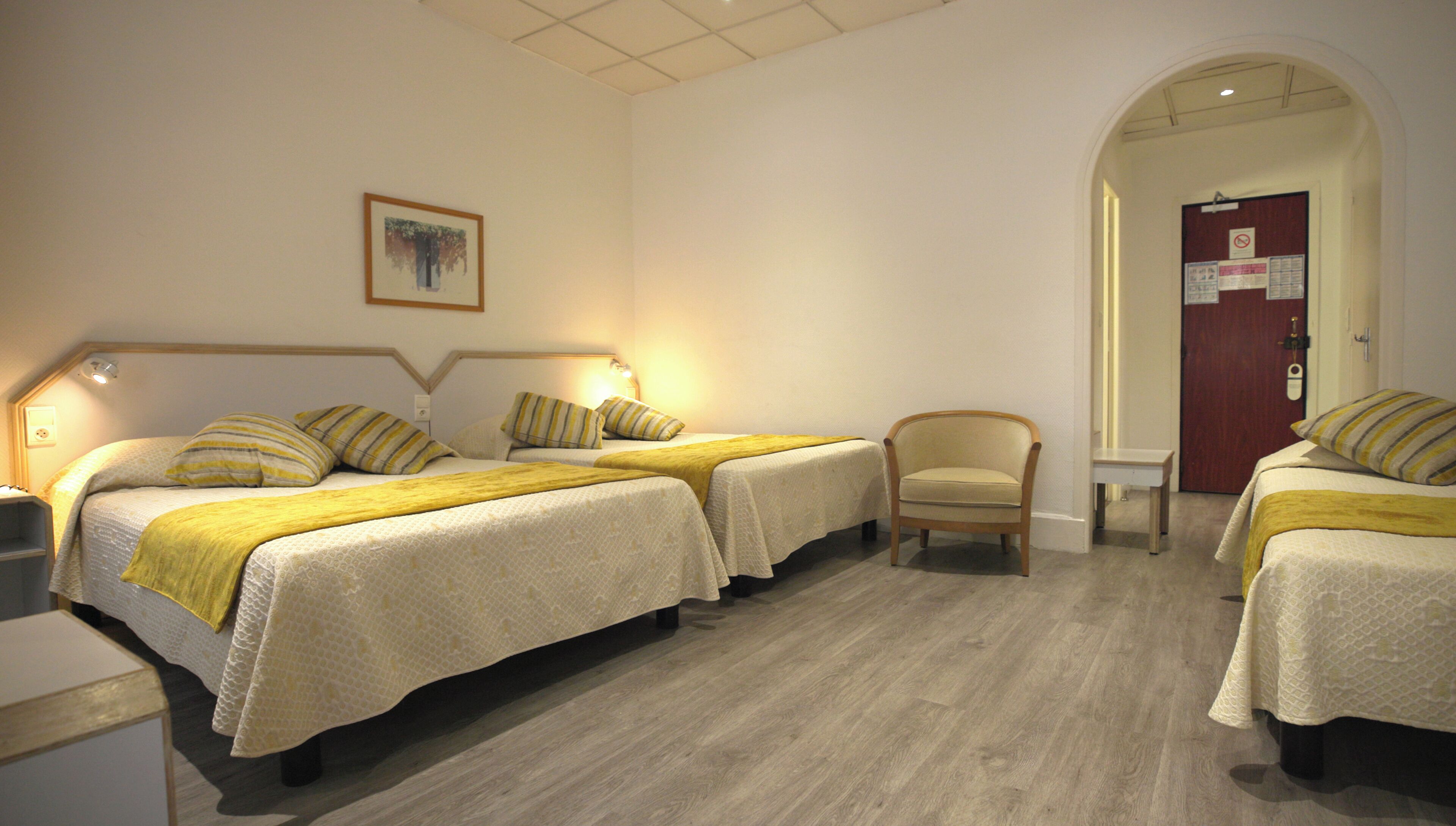 A hotel room with two beds, a chair, and a desk.