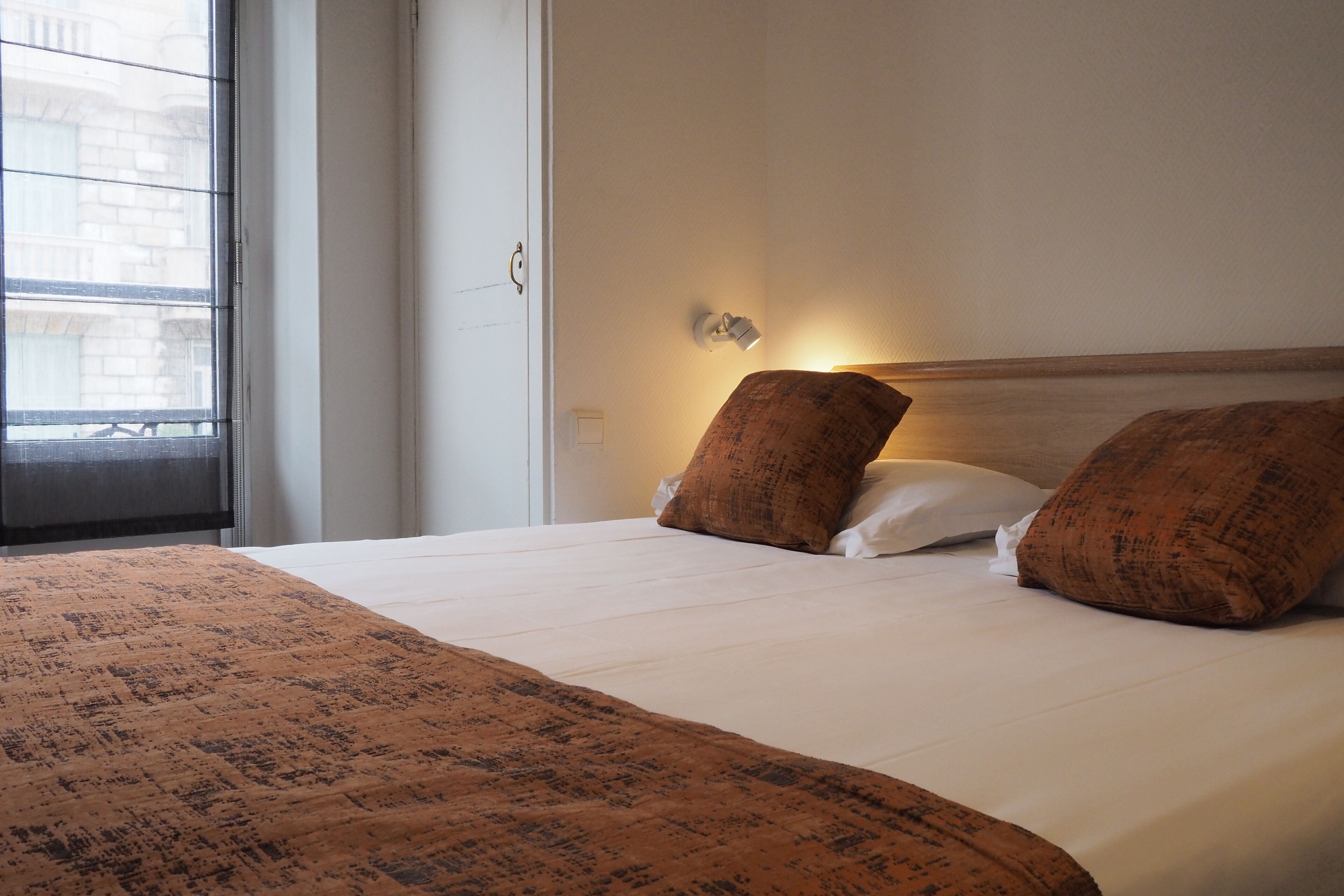 A neatly made bed with a patterned bedspread, two pillows, and a bedside lamp.
