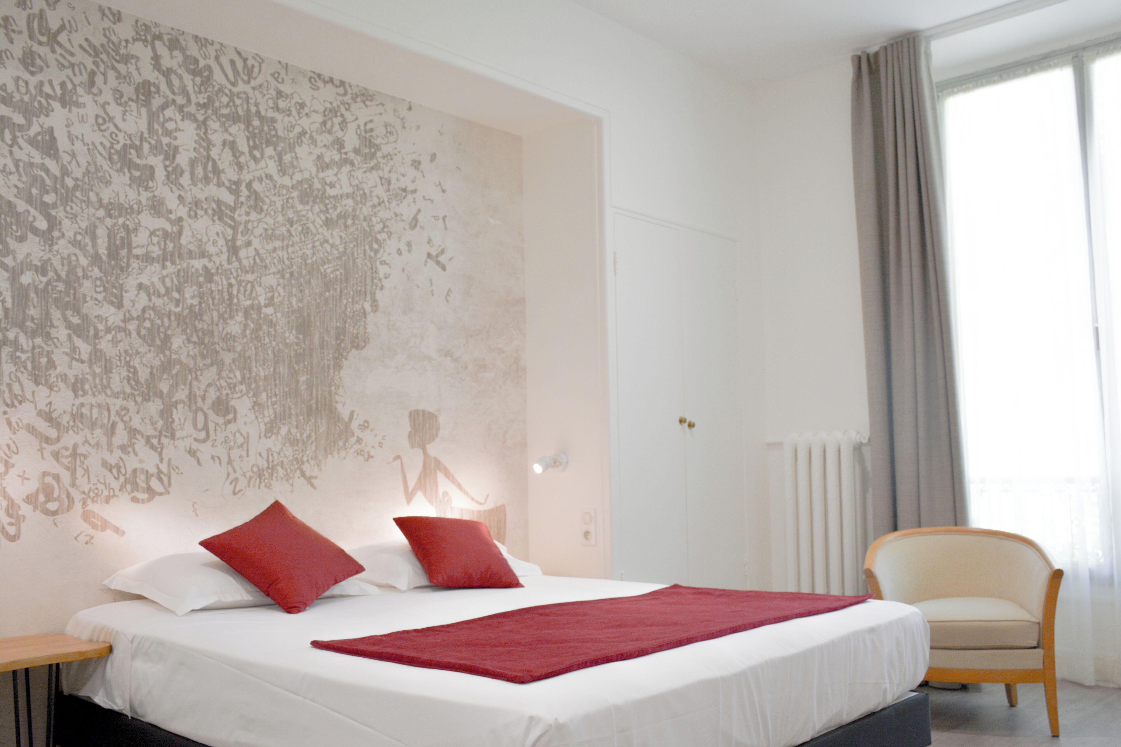 Una habitación de hotel con una cama grande, una silla y una pared con un mural.