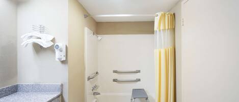 A bathroom with a bathtub, a shower, a towel rack, and a step stool.