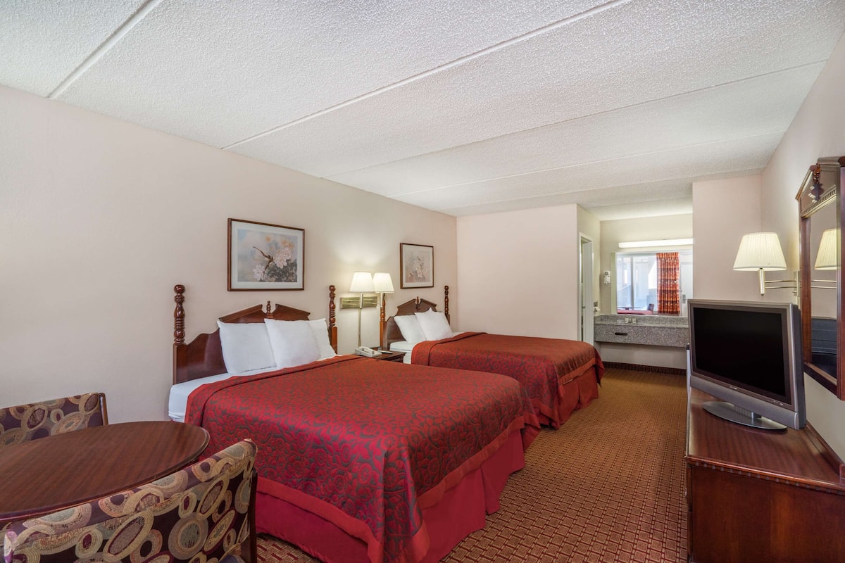 A hotel room with two beds, a TV, a desk, and a chair.