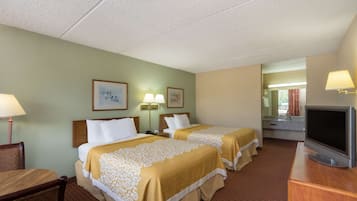 Habitación de hotel con dos camas, televisión, escritorio y baño visible a través de una puerta abierta.
