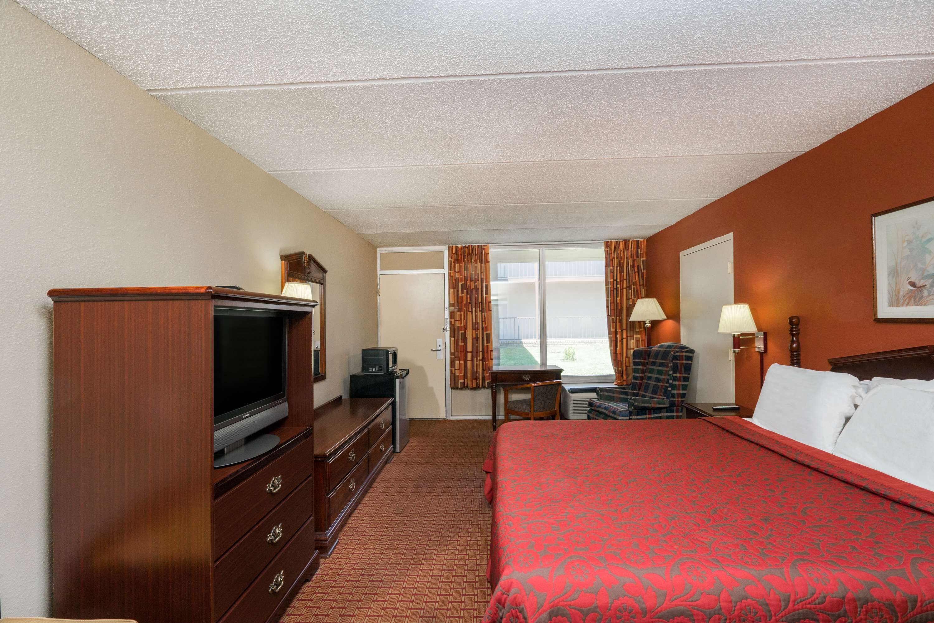 Una habitación de hotel con cama, televisión, escritorio y una silla.
