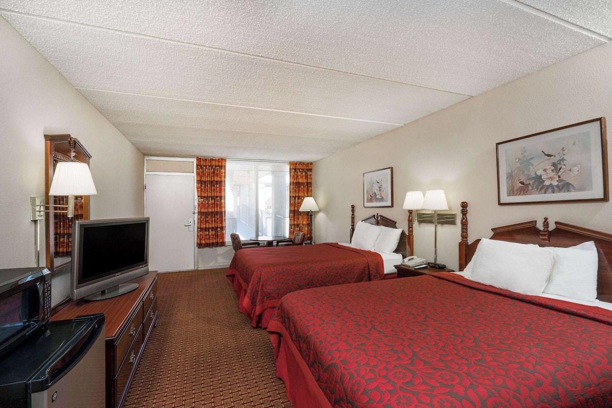 A hotel room with two beds, a television, a desk with a computer, and a microwave.