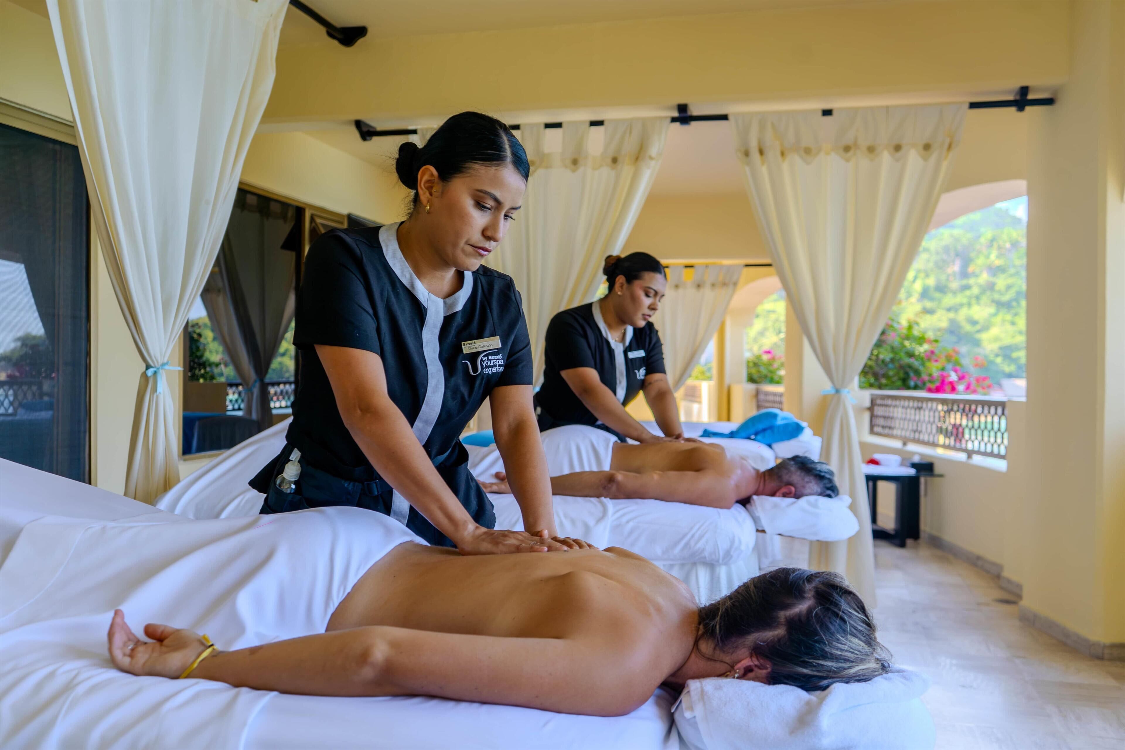 Une salle de massage où deux clients reçoivent des massages du dos.