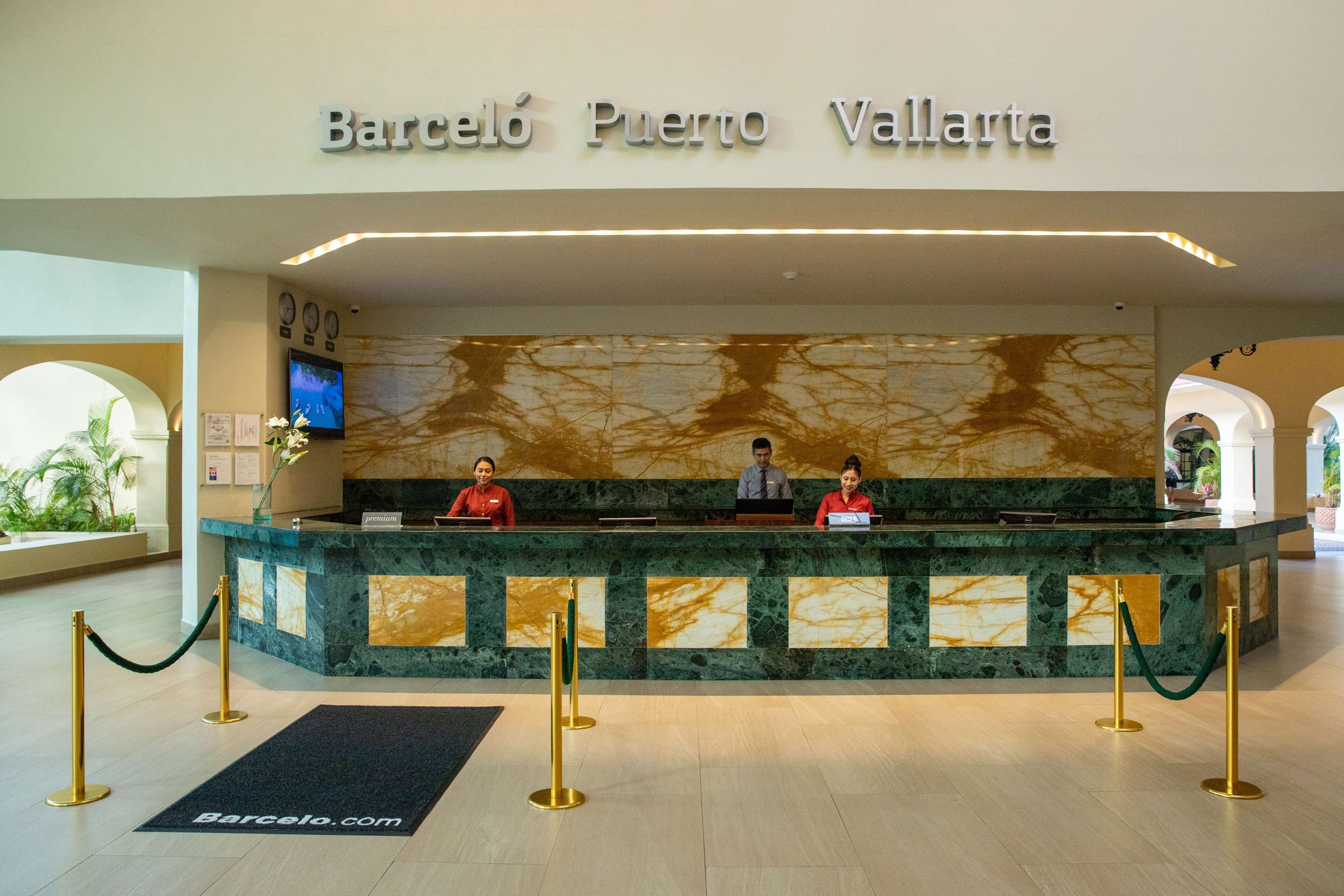 A hotel reception desk with a marble counter and a sign above it that reads "Barcelona Puerto Vallarta".