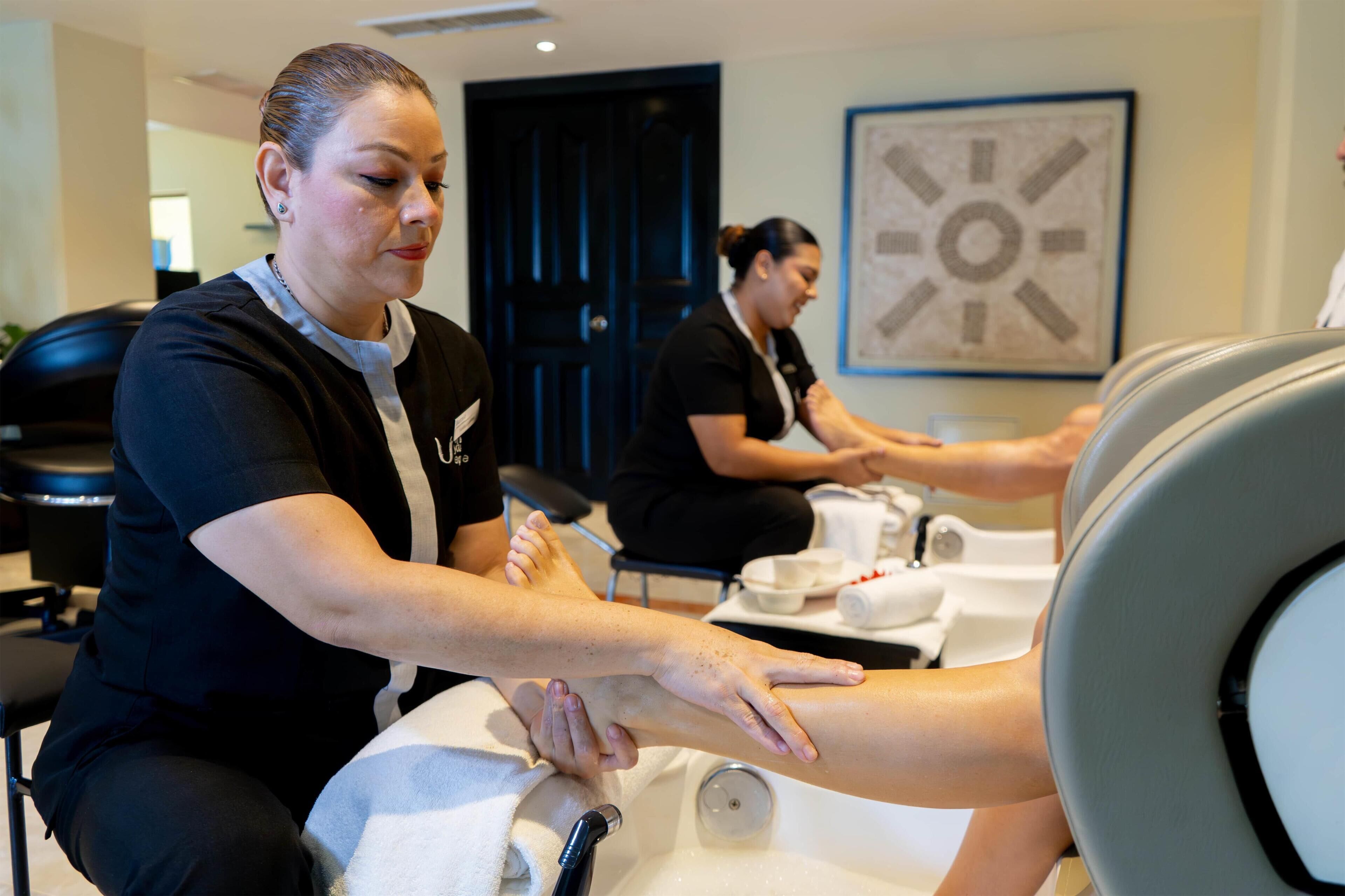 Une salle de massage équipée d’une table de massage, d’un bain de pieds et d’une horloge murale.