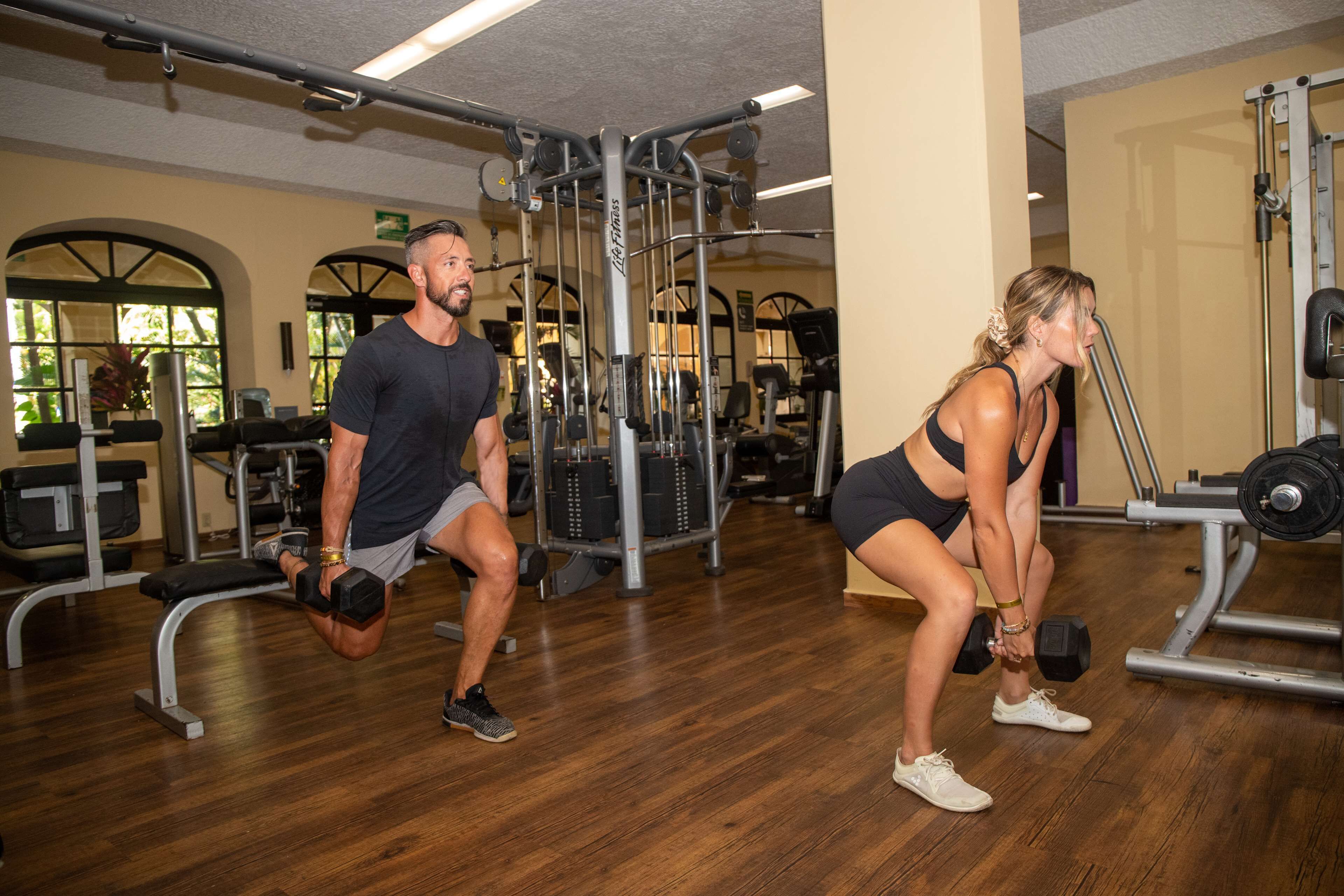 Een sportschool met houten vloeren en diverse fitnessapparatuur.