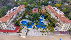 A resort with multiple swimming pools, palm trees, and a beach area.