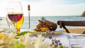Une table dressée avec un plat de homard, des verres à vin et une vue sur la mer.