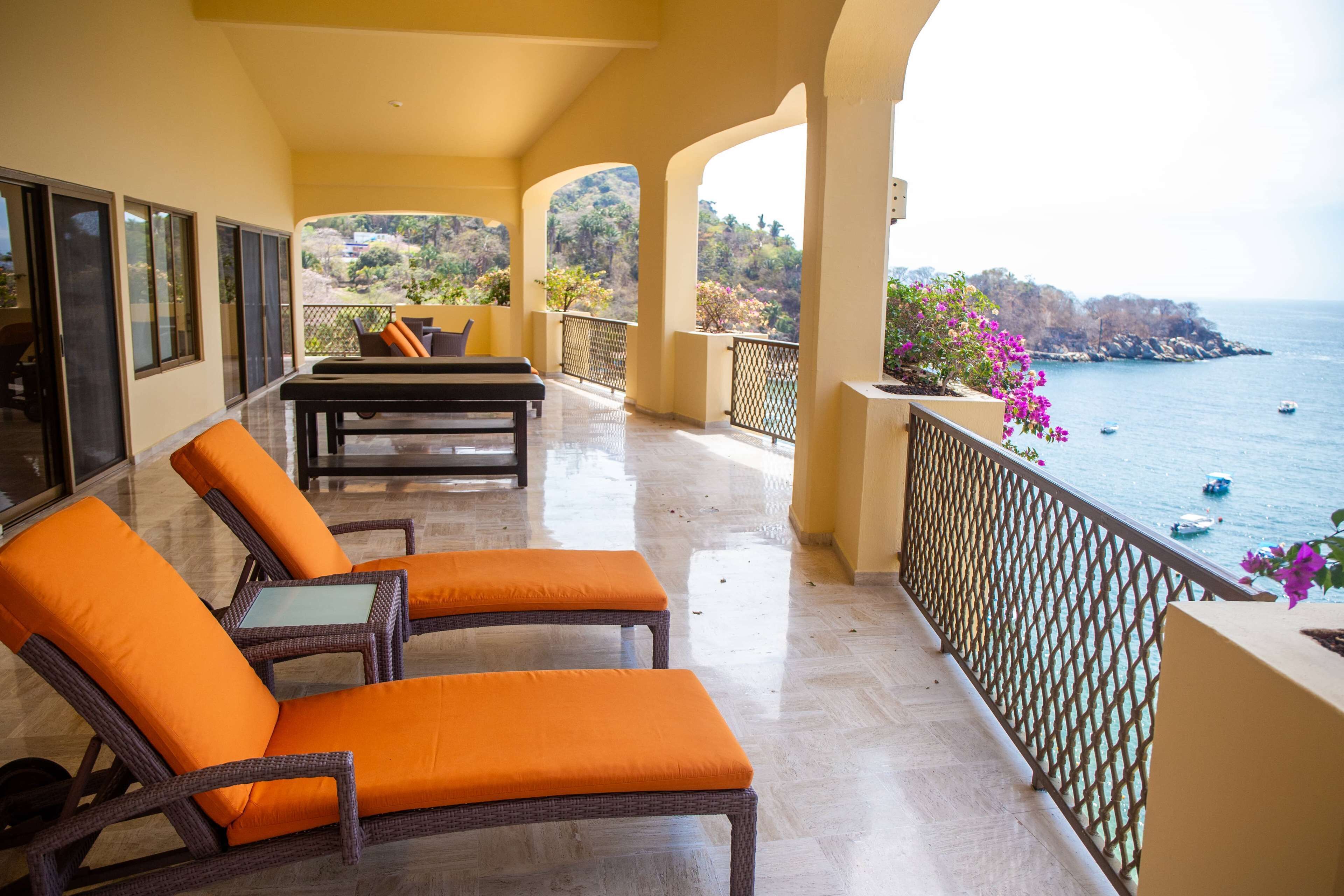 A balcony with wicker furniture and a view of the sea.