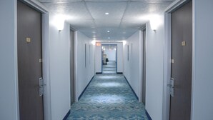Un pasillo largo y estrecho con alfombra estampada y puertas a ambos lados.