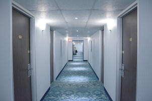 Un pasillo largo y estrecho con alfombra estampada y puertas a ambos lados.
