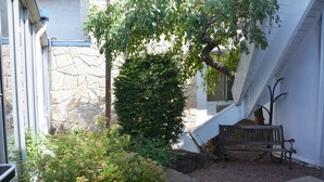 Un muro de piedra, un banco de madera y un árbol en un patio.