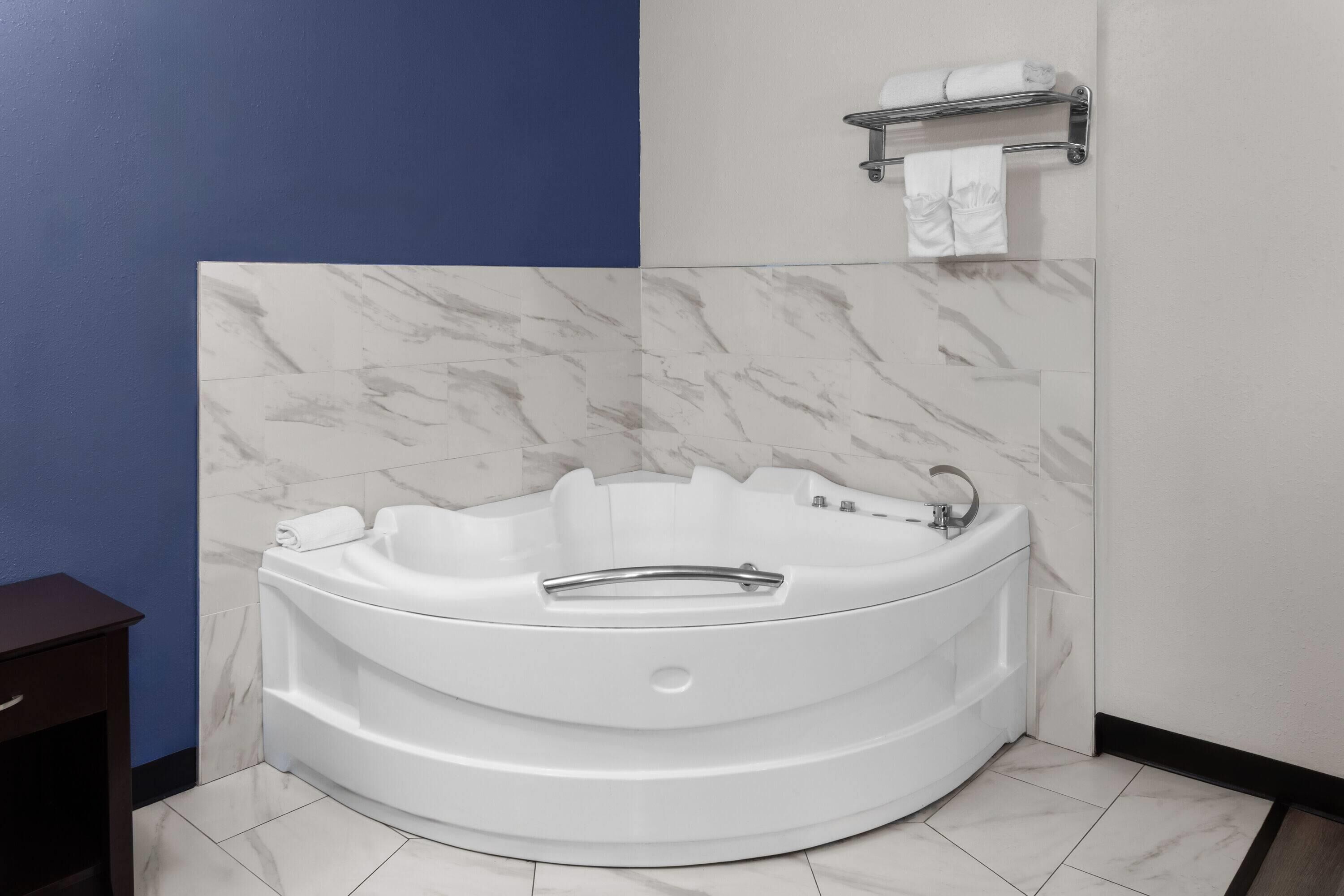 Een badkamer in hoekopstelling met een vrijstaand bad, een handdoekhouder en een toilet.