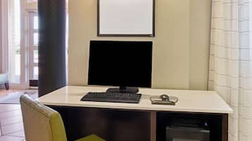 A hotel room with a desk, computer, and printer.