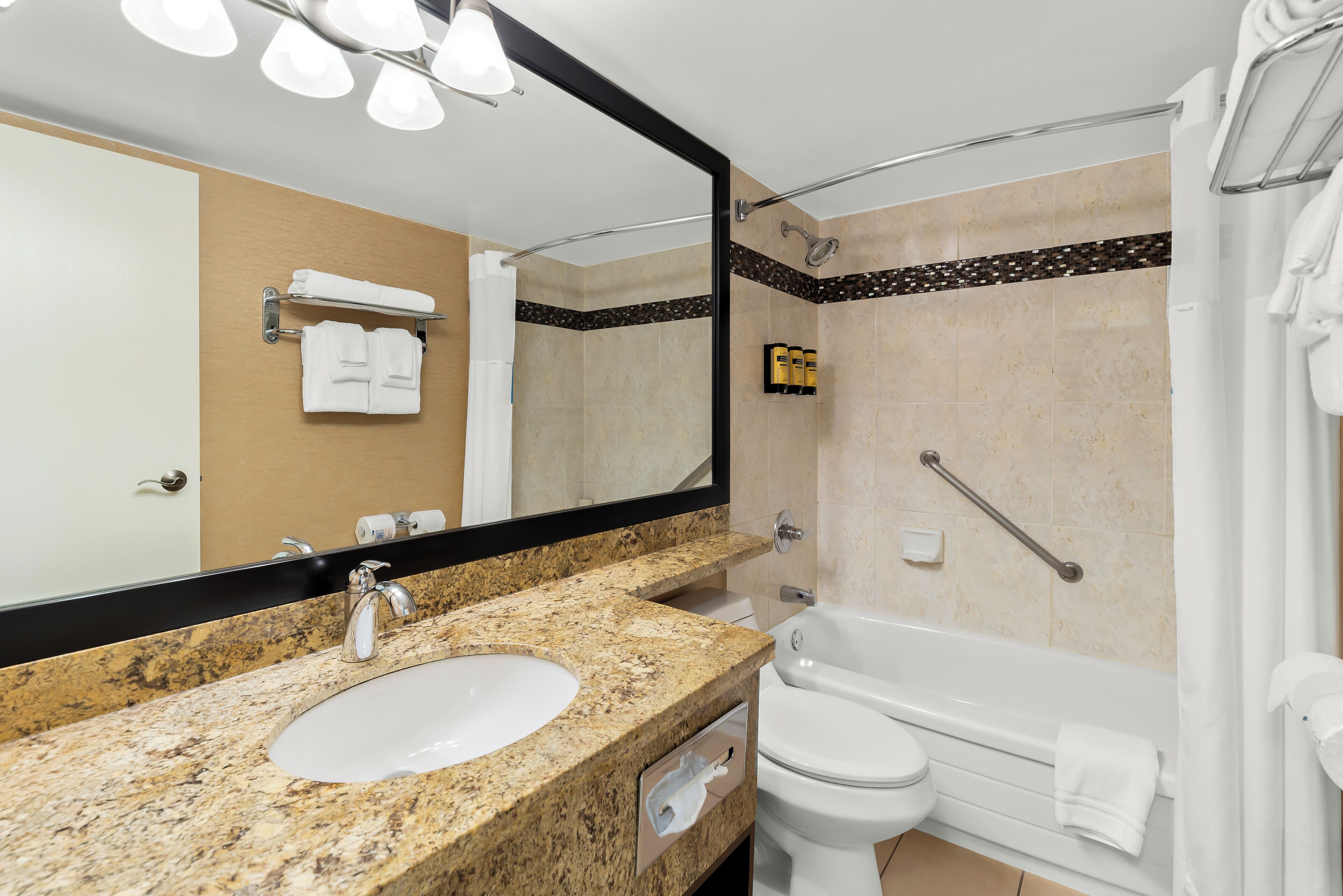 Une salle de bain avec un lavabo à vasque en granit, des toilettes blanches et une baignoire.