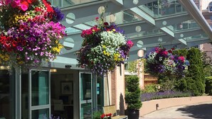 A hotel entrance with hanging flower baskets, a bench, and a glass door. - Best Western Plus Inner Harbour (Victoria)