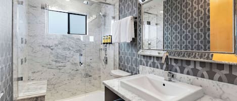 Une salle de bain moderne avec une douche à parois de verre, un grand lavabo et des toilettes.