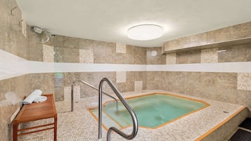 A spa area with a hot tub, a wooden bench, and a metal ladder.