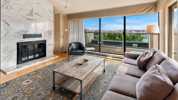 A modern living room with a fireplace, a sofa, a coffee table, and a large window offering a view of the city. - Best Western Plus Inner Harbour (Victoria)