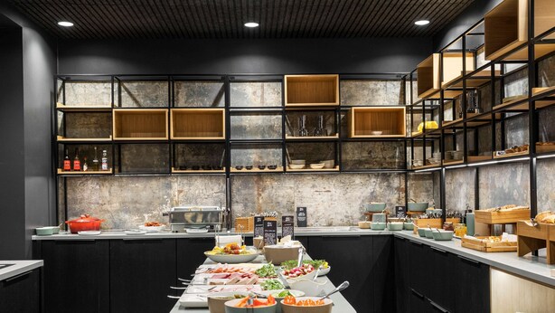 A modern kitchen with a central island, black cabinets, and wooden shelves. - Best Western Plus Hotel Eyde (Herning)