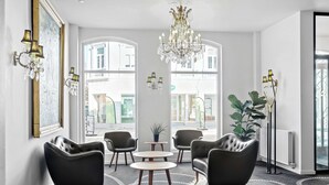 A modern interior with leather armchairs, a chandelier, and large windows offering a view of the street. - Best Western Plus Hotel Eyde (Herning)