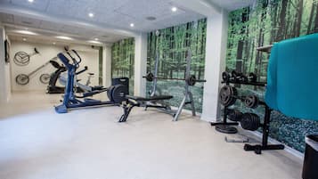 Un gimnasio con equipo de ejercicios, incluyendo una cinta de correr, una elíptica y un banco de pesas.