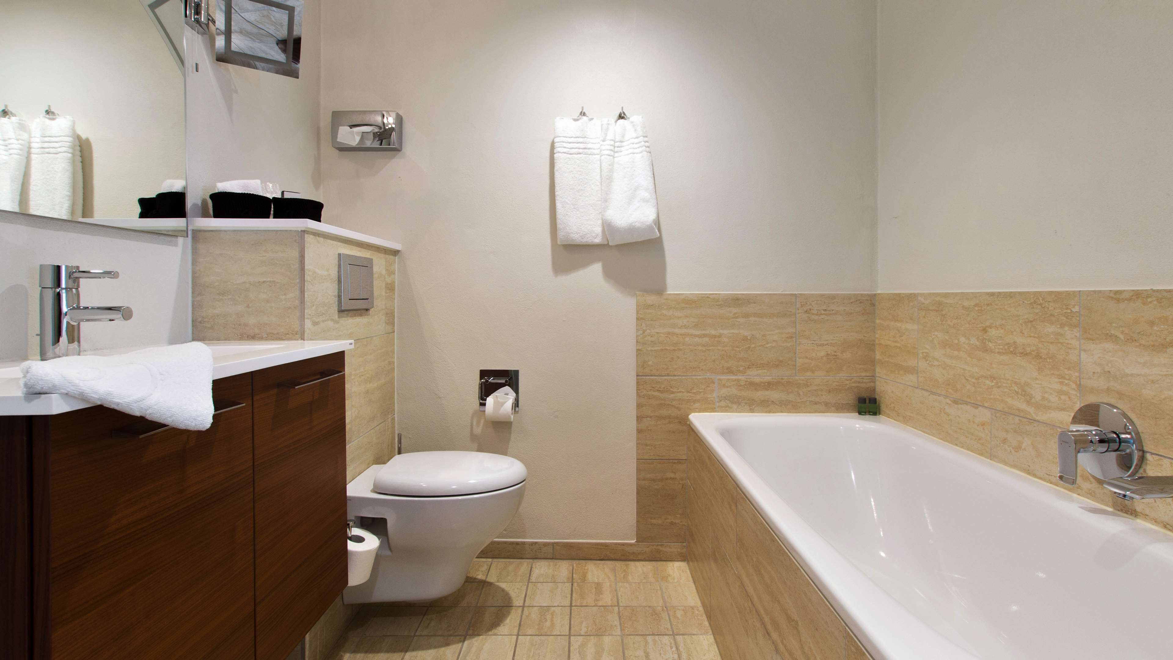 A modern bathroom with a bathtub, toilet, and vanity.