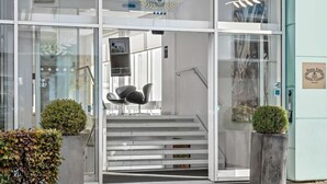 A modern hotel entrance with glass doors, a staircase, and two potted plants. - Best Western Plus Hotel Eyde (Herning)
