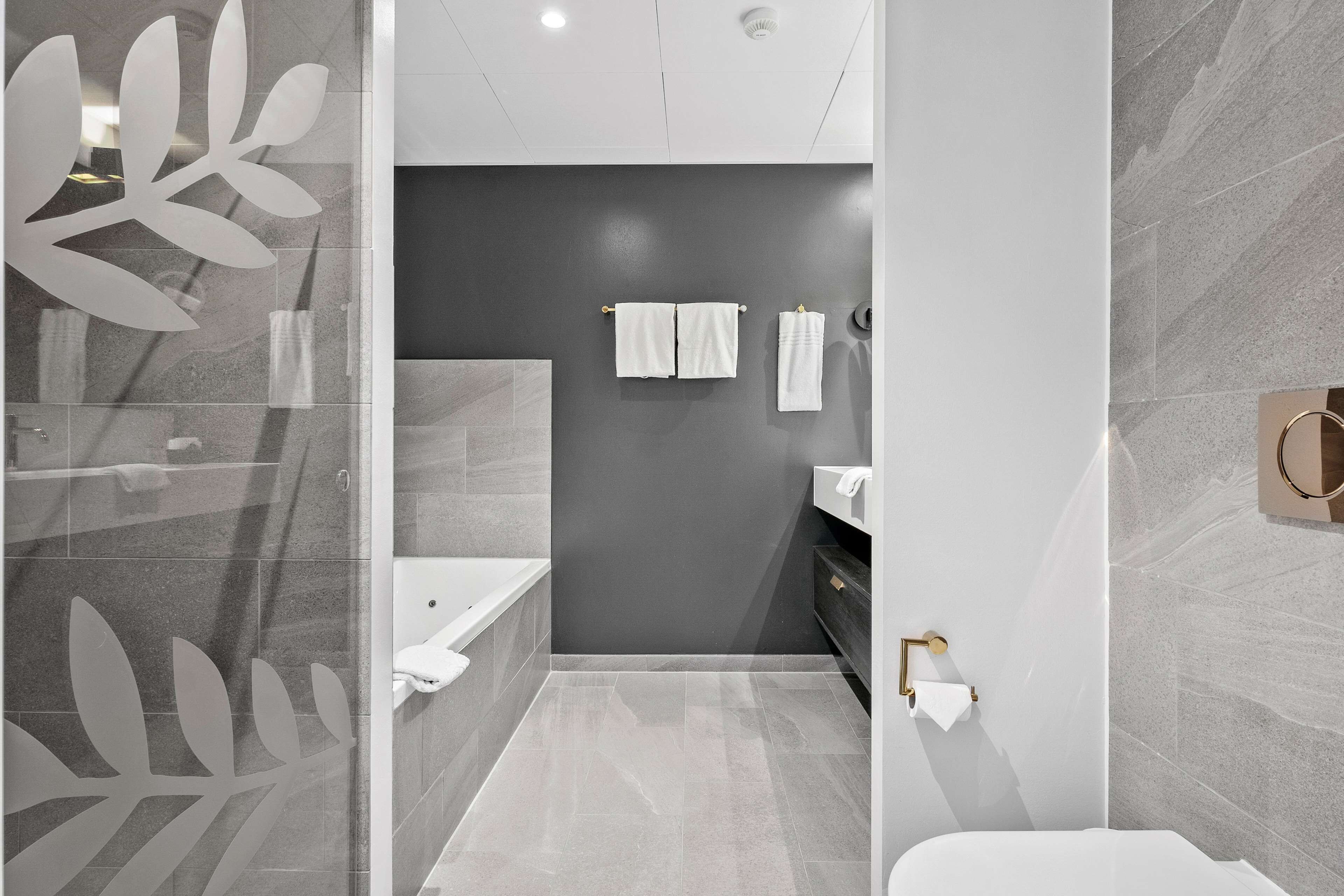Un baño moderno con cabina de ducha de vidrio, bañera, inodoro y lavabo.
