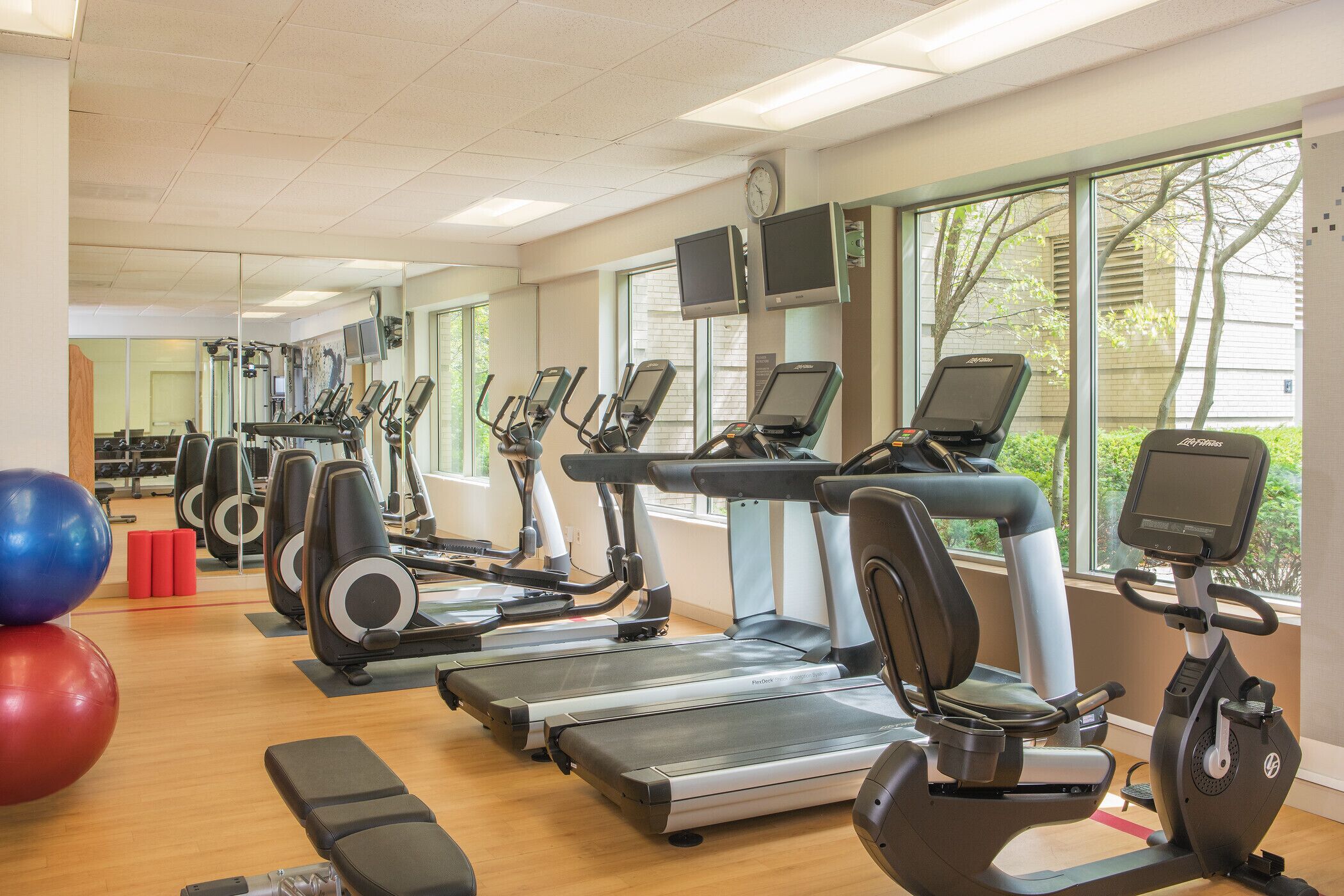 Een sportschool met loopbanden, elliptische trainers en fitnessballen.