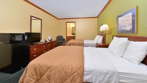 Une chambre d’hôtel avec un lit, un bureau équipé d’un ordinateur, une chaise, une lampe et un tableau au mur.