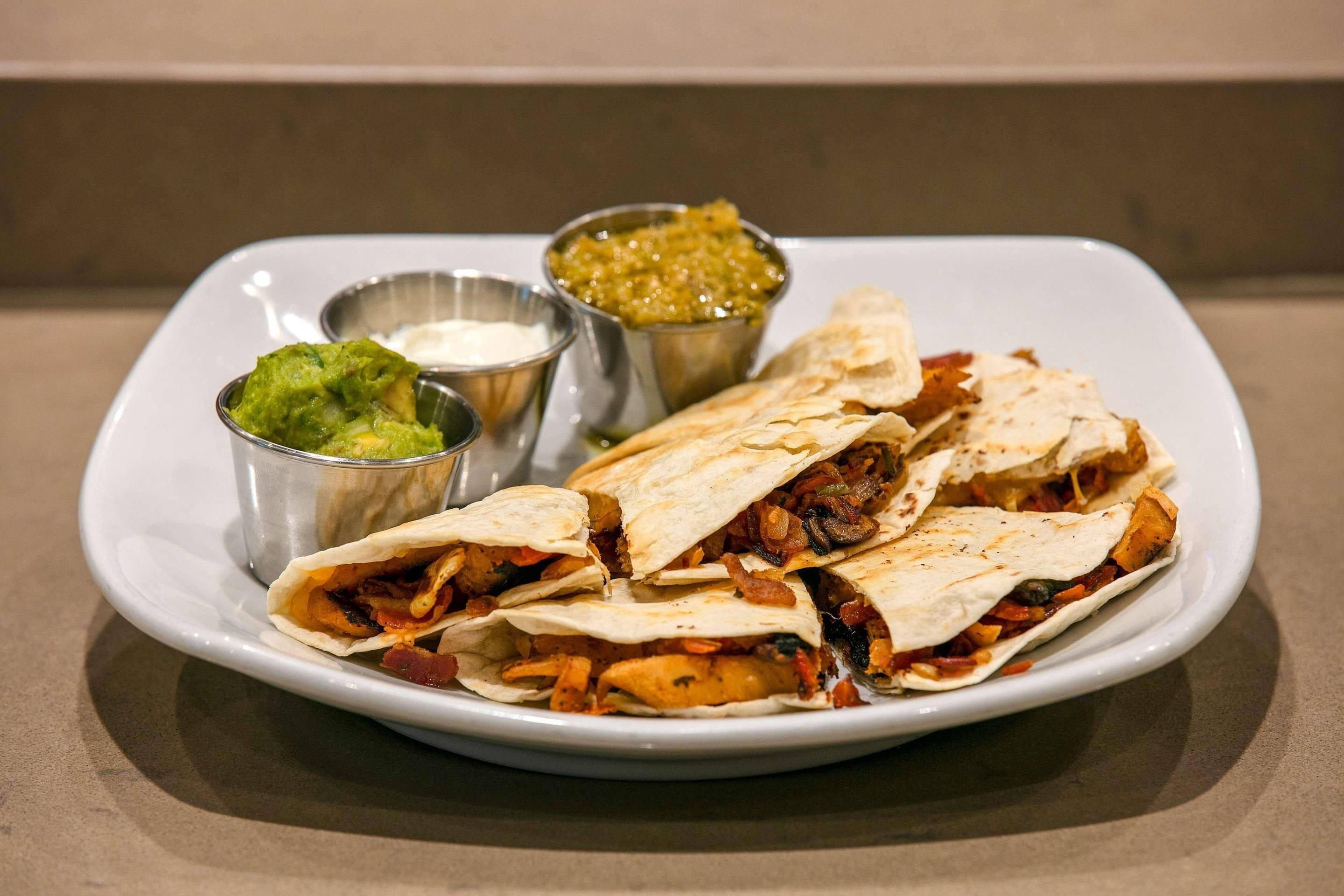 A plate of quesadillas with refried beans and guacamole.