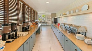 A modern kitchen with a long counter, coffee makers, and a variety of food items. - Country Inn & Suites by Radisson, San Diego North, CA (San Diego)
