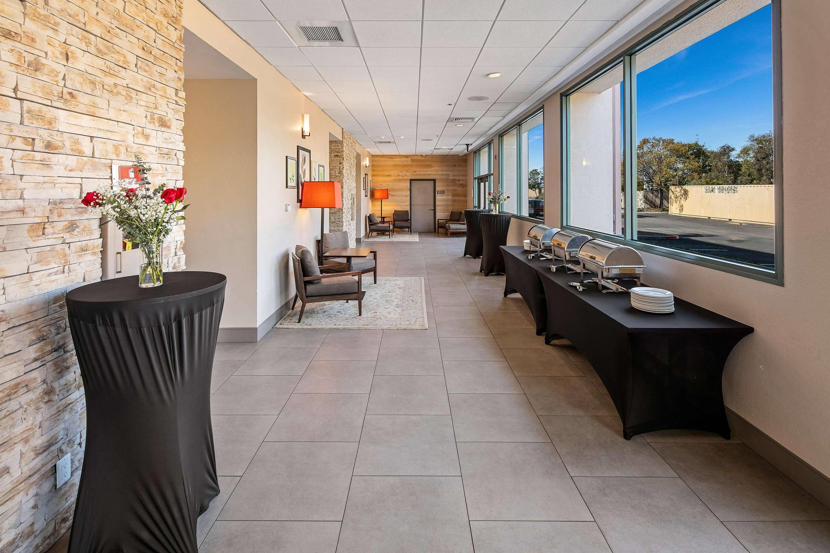 A modern hotel lobby with a brick wall, a reception desk, a seating area, and a buffet table.