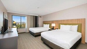 A hotel room with two beds, a desk with a computer, a TV, and a large window offering a city view. - Country Inn & Suites by Radisson, San Diego North, CA (San Diego)
