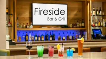 A bar area with a sign reading 'Fireside Bar & Grill' and various colorful drinks on the counter.