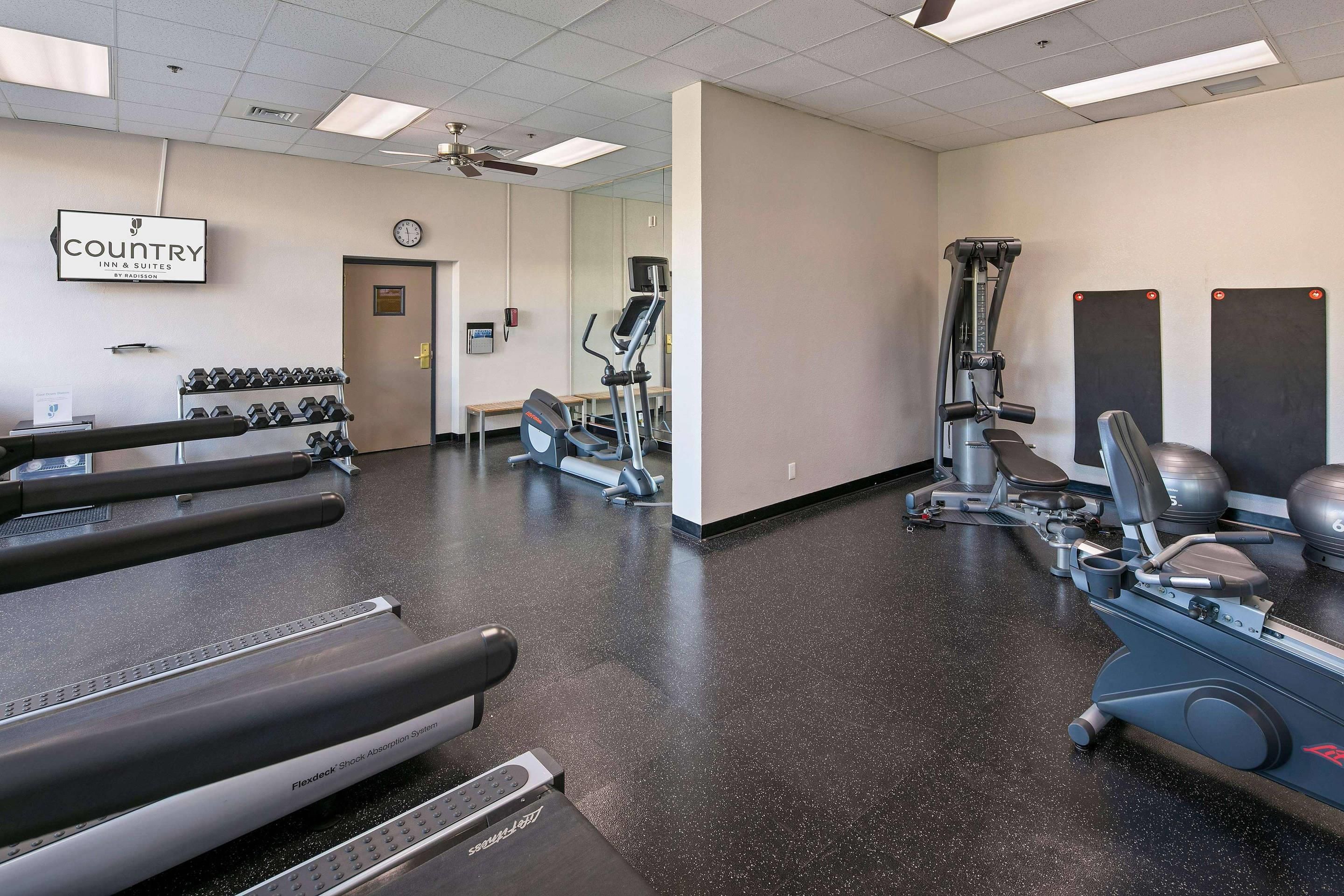 A gym with treadmills, weight machines, and a wall clock.