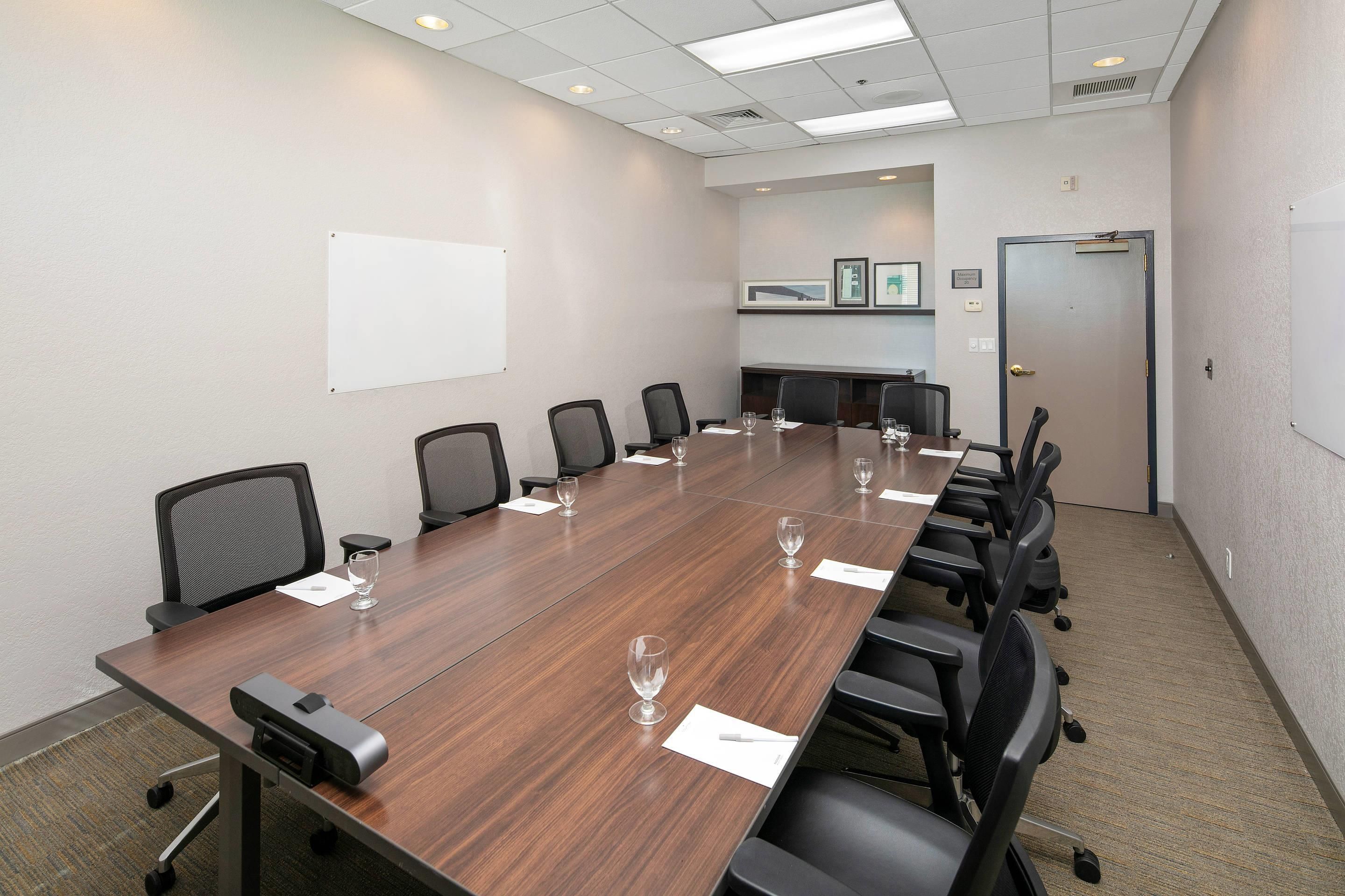 Una sala de conferencias con una mesa larga, sillas y una pizarra.