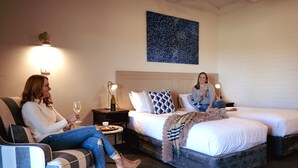 Habitación de hotel con dos camas, una mesita de noche, una lámpara y un cuadro en la pared.