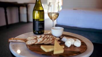 A round table with a bottle of wine, a glass of wine, and a plate of cheese and crackers.