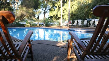 Una piscina al aire libre, sillones reclinables de piscina